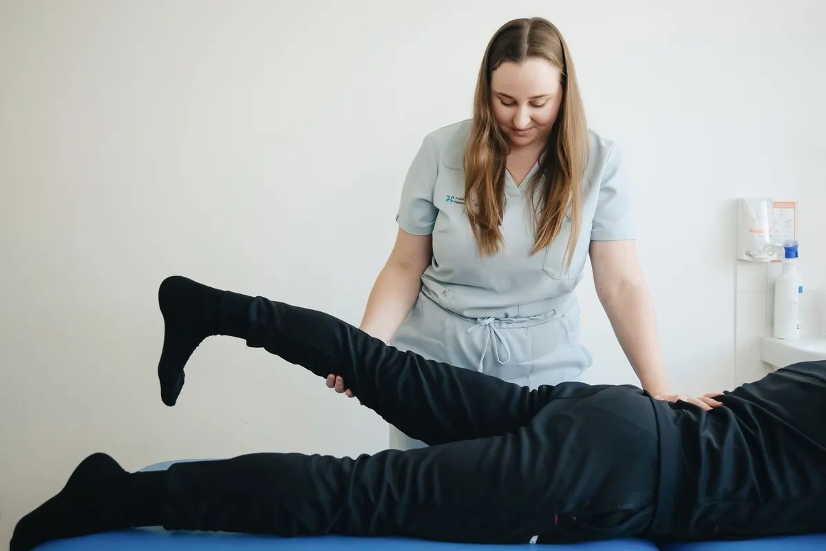 A therapist stretching a patient's leg on a treatment table
